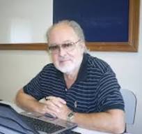 Sylvio Silveira Santos sentado à mesa, diante de um quadro